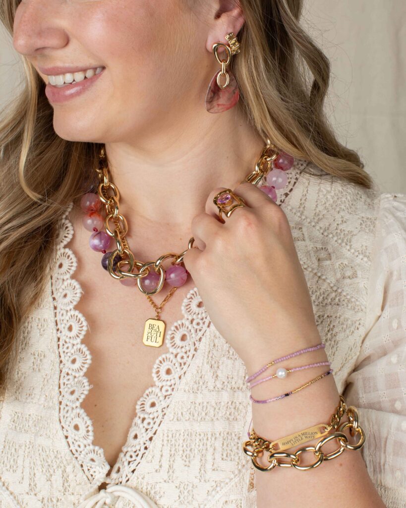 Danica pink beaded statement necklace and Orla marbled resin earrings styled with layered gold jewelry and a cream lace blouse for fall fashion.