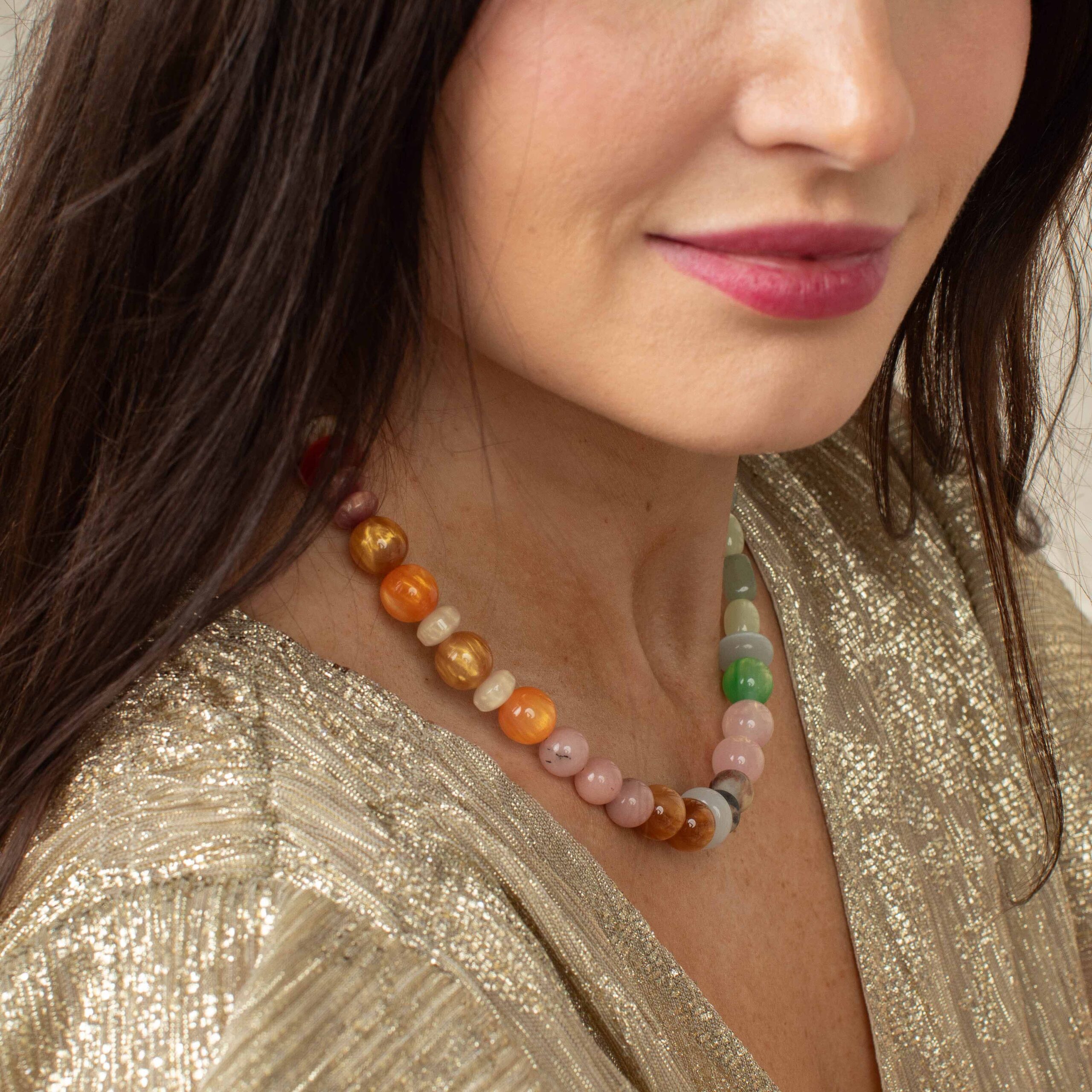 Woman wearing the colorful Justine Necklace with natural elements and glass beads in soft pastel and earthy tones.