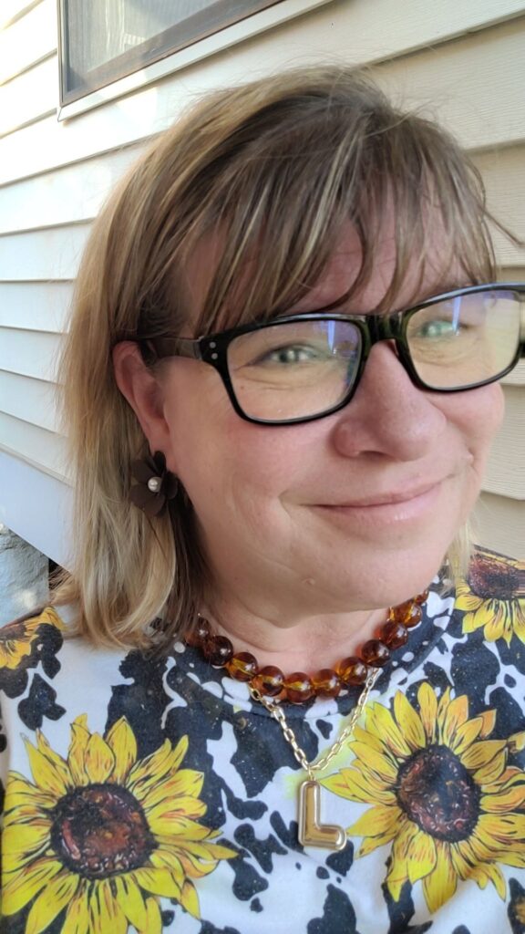 Woman wearing the Dinah chunky amber resin bead necklace layered with a gold initial pendant, showing how oversized beaded necklaces are an easy way to add warmth and texture to Fall 2026 outfits.