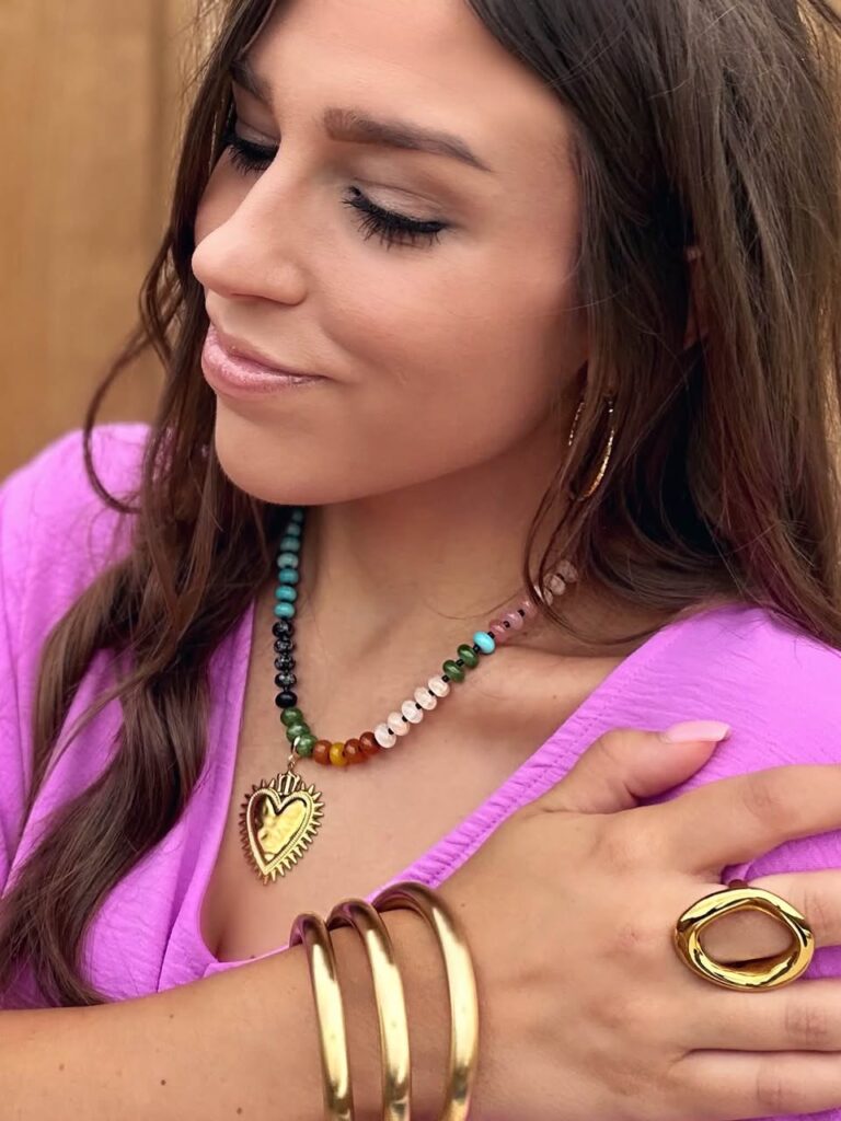 Model wearing the Justine colorful beaded necklace with a gold heart pendant, demonstrating the Fall 2026 trend of layering colorful natural stone and glass bead jewelry with bold gold accessories.