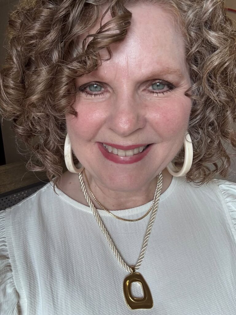 Smiling woman wearing the gold Louisa cord necklace layered with a delicate gold chain over a white top.