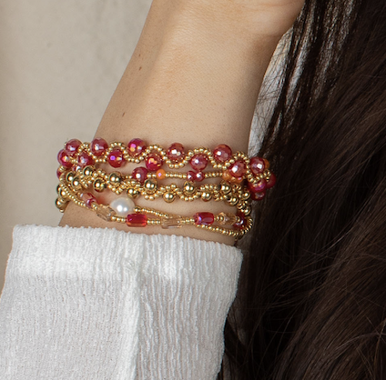 Close-up of a woman wearing the Scarlett bracelet stack featuring red, pink, gold, and pearl-accented beads.