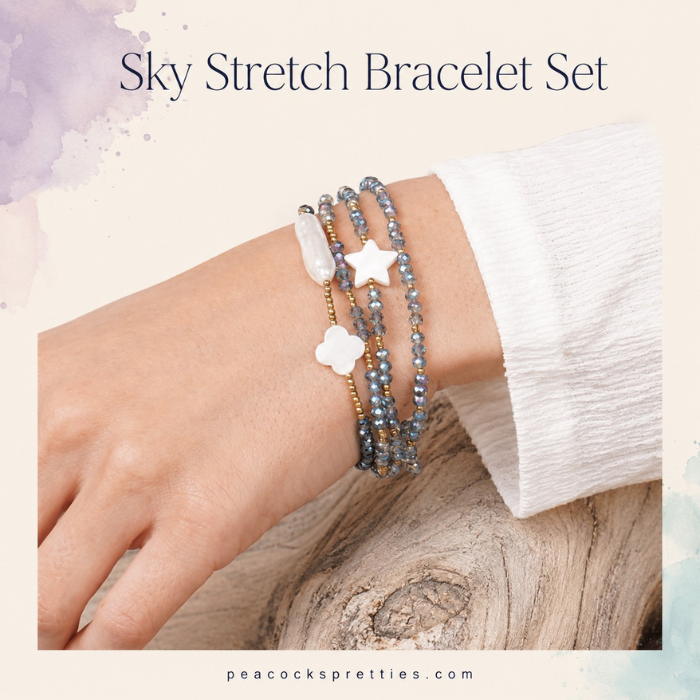 Sky Stretch Bracelet Set worn on the wrist with blue-gray faceted beads, gold accents and white pearl-like shapes.