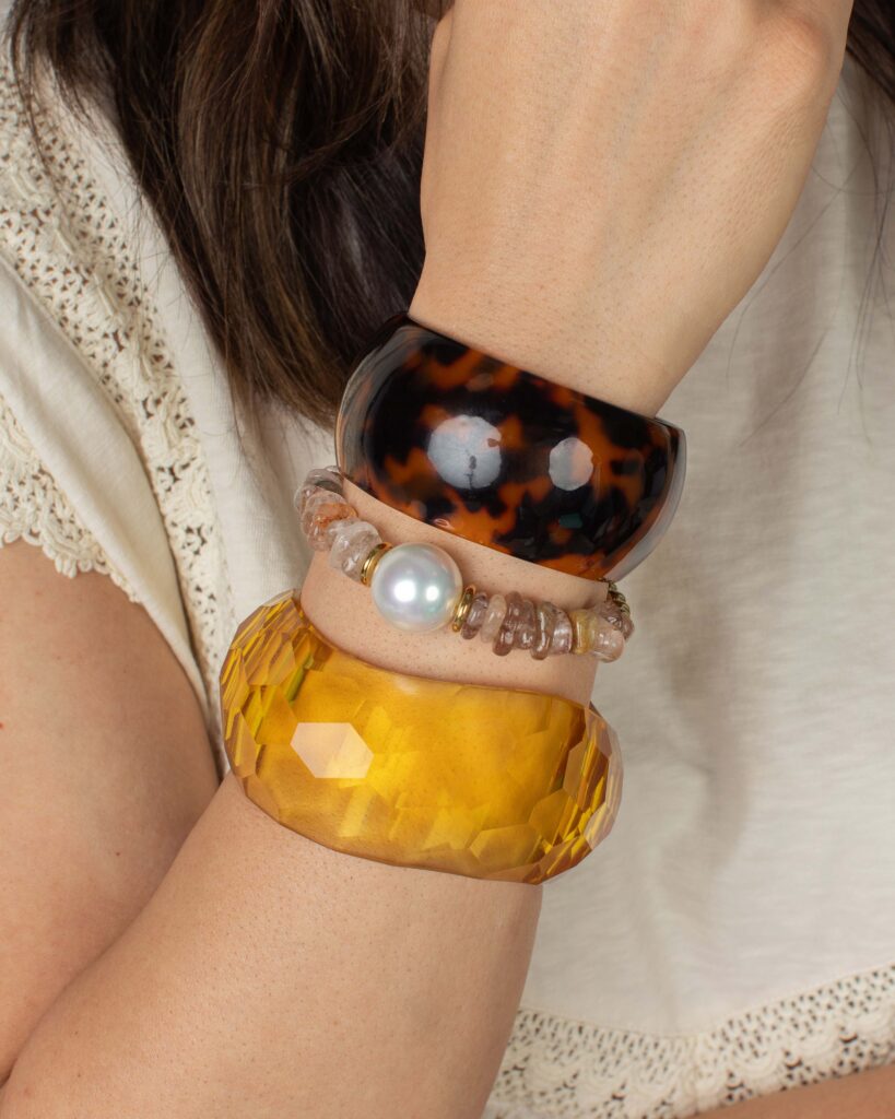 Tortoise and honey-gold resin cuffs stacked with a pearl bracelet for a bold pre-fall look.