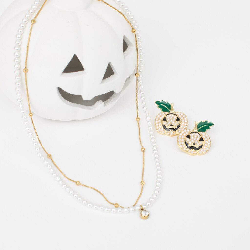 Gold and pearl Maci layered necklace styled with pearl jack-o’-lantern earrings and a white Halloween pumpkin.