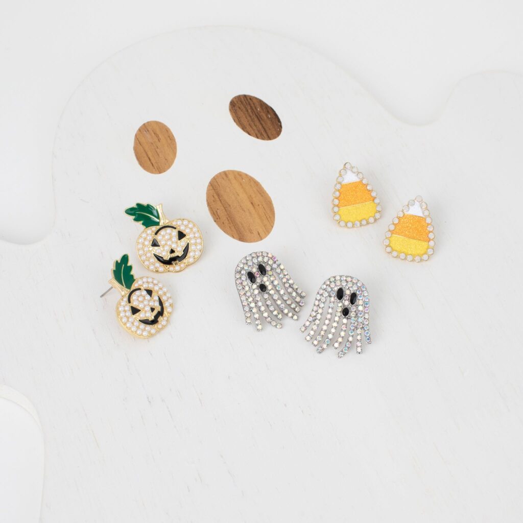 Three Halloween earring styles displayed together: rhinestone ghosts, pearl jack-o’-lanterns, and orange-and-yellow candy corn earrings.
