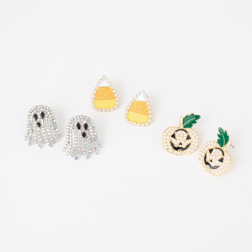 Rhinestone ghost, pearl jack-o’-lantern, and candy corn earrings arranged together on a clean white background.