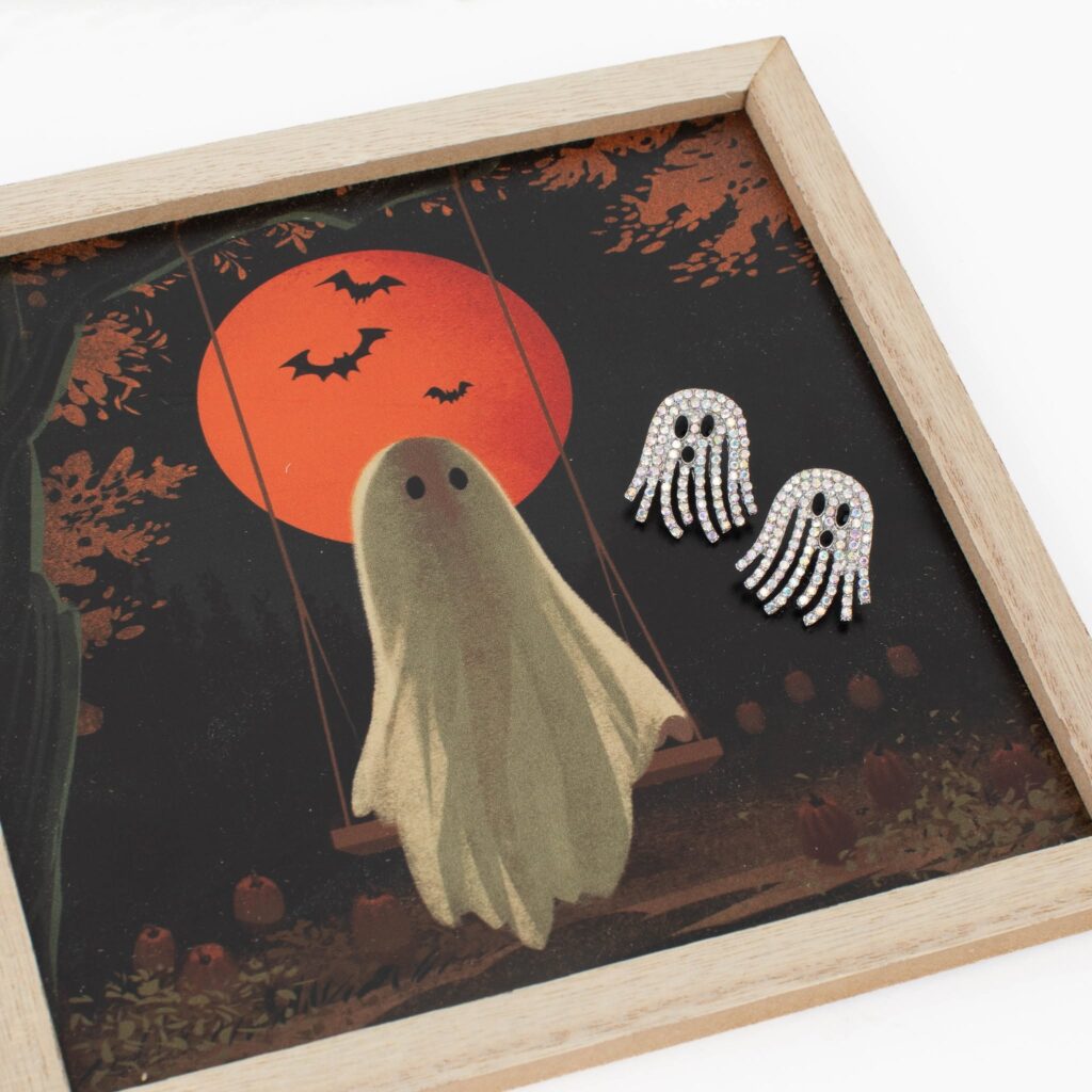 Silver rhinestone ghost earrings displayed on framed vintage Halloween artwork featuring a ghost, orange moon, and bats.