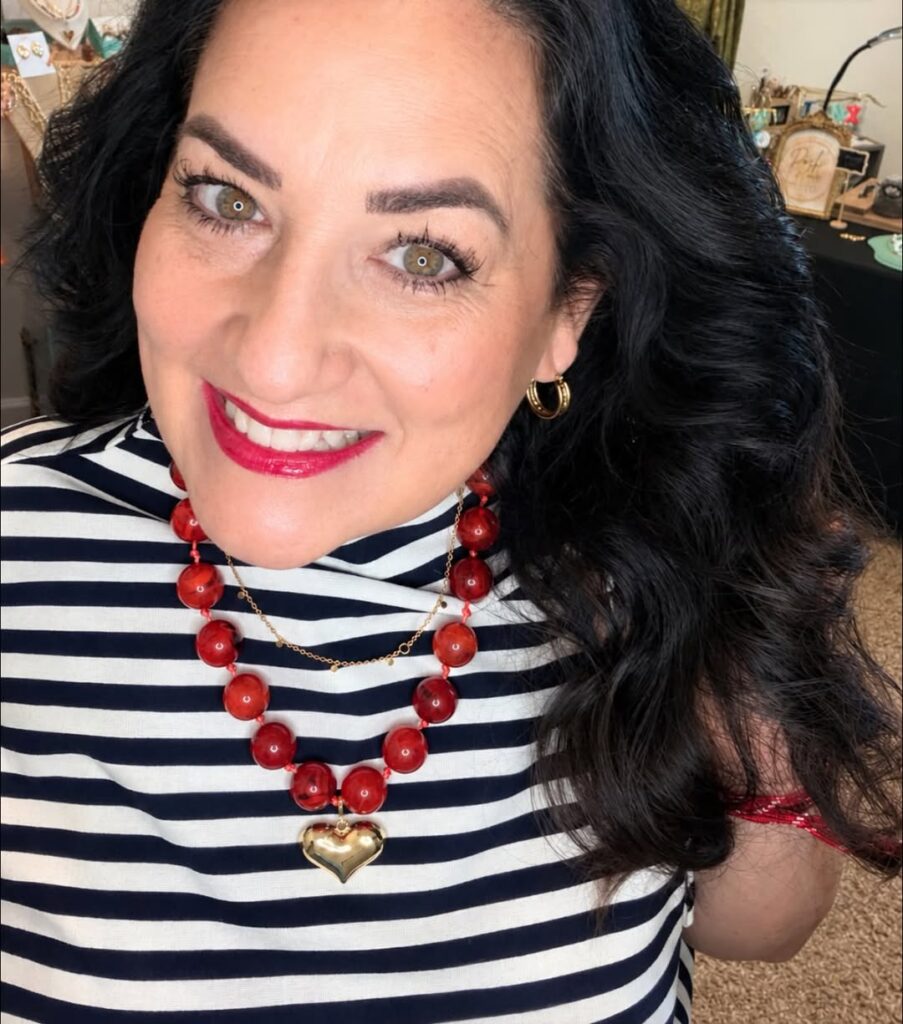 Cherry Bauble Necklace styled with a striped top, a separate gold heart charm, and other jewelry
