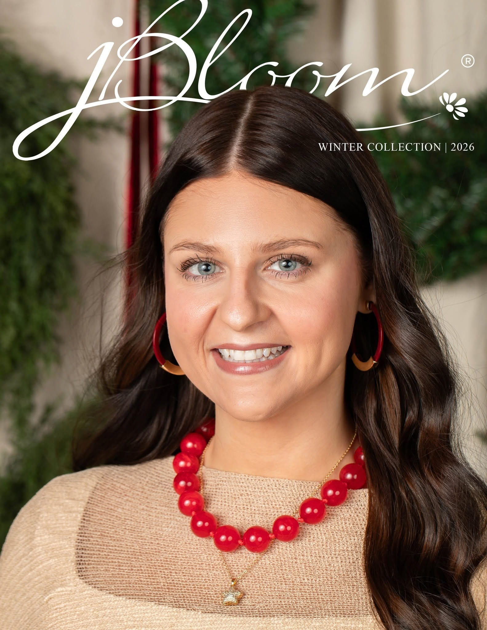 jBloom Winter Collection 2026 catalog cover featuring a woman wearing red and gold hoop earrings, a bold red bead necklace, and a delicate gold pendant over a beige sweater.