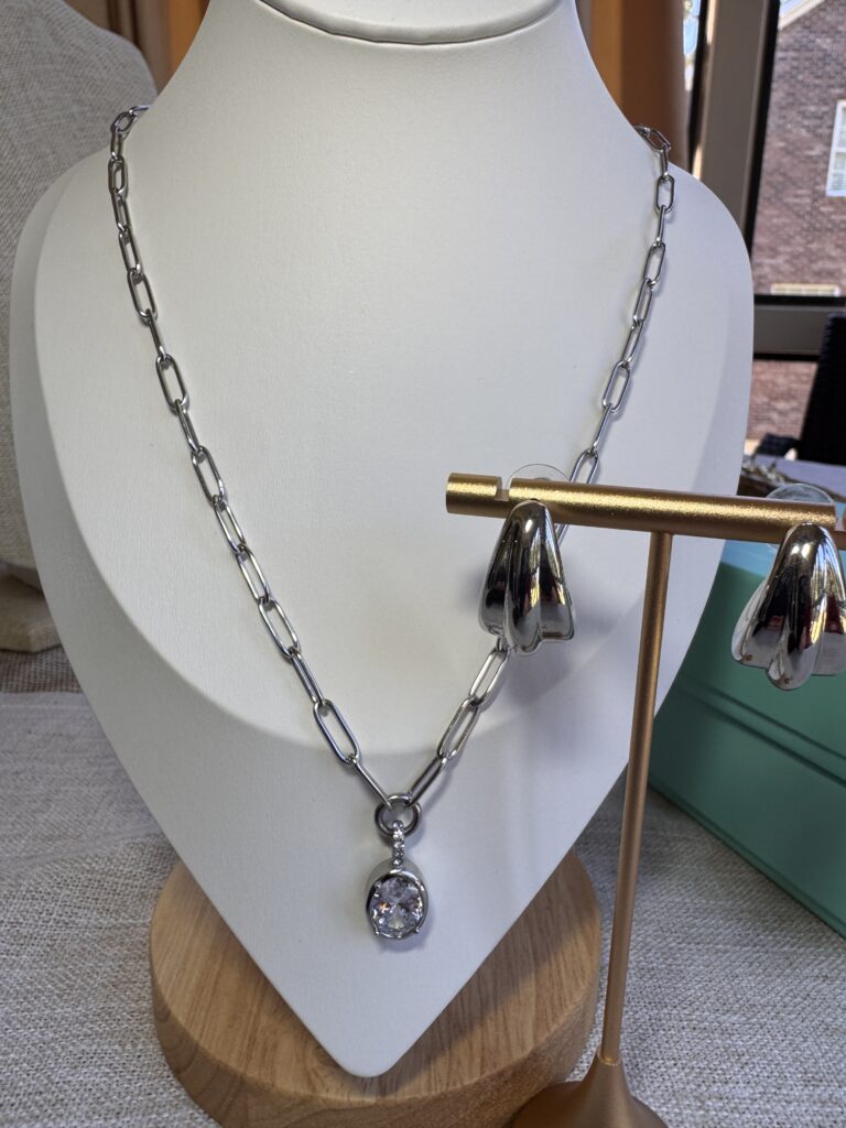 Silver Danielle Necklace with a zircon drop on a white display bust beside matching silver James Earrings