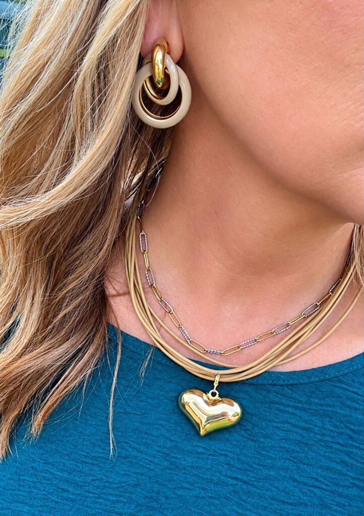 Dawn multi-strand necklace with gold Bubble Heart Charm and Petra statement earrings worn with a teal top.