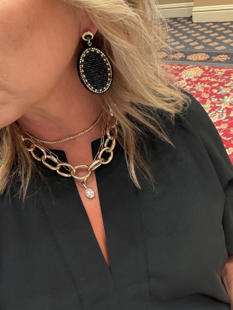Kali statement earring styled with a black blouse and separate gold necklaces
