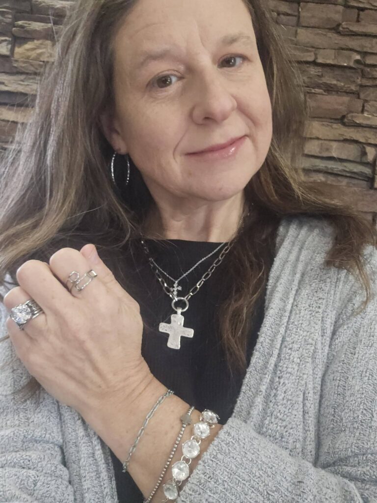 Lora Necklace with a silver Hammered Cross Charm, styled with separate layered jewelry