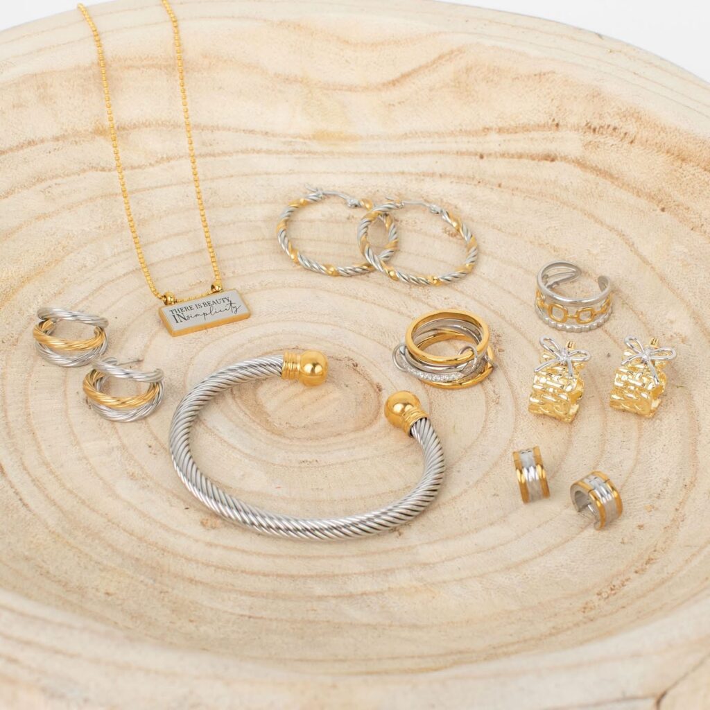 Gold and silver mixed-metal jBloom jewelry collection arranged on a pale wood tray